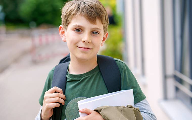 Boy holding books at school